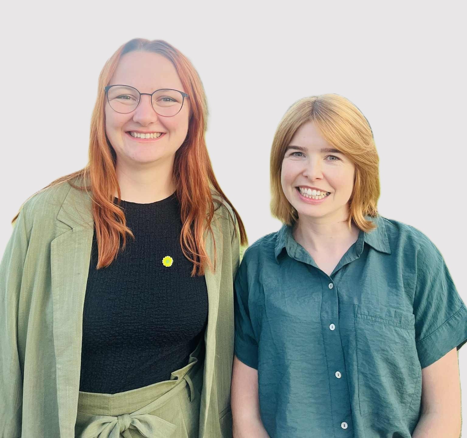 Zwei junge Frauen blicken in die Kamera und lächeln.