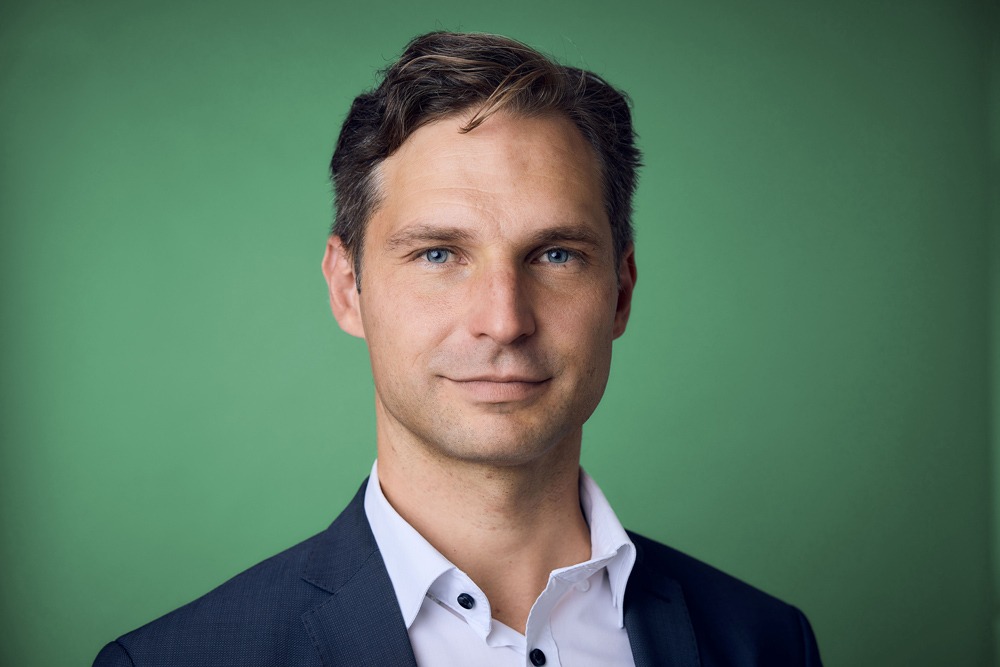 Brustbild mit grünem Hintergrund, Toni Schuberl blickt frontal in die Kamera.